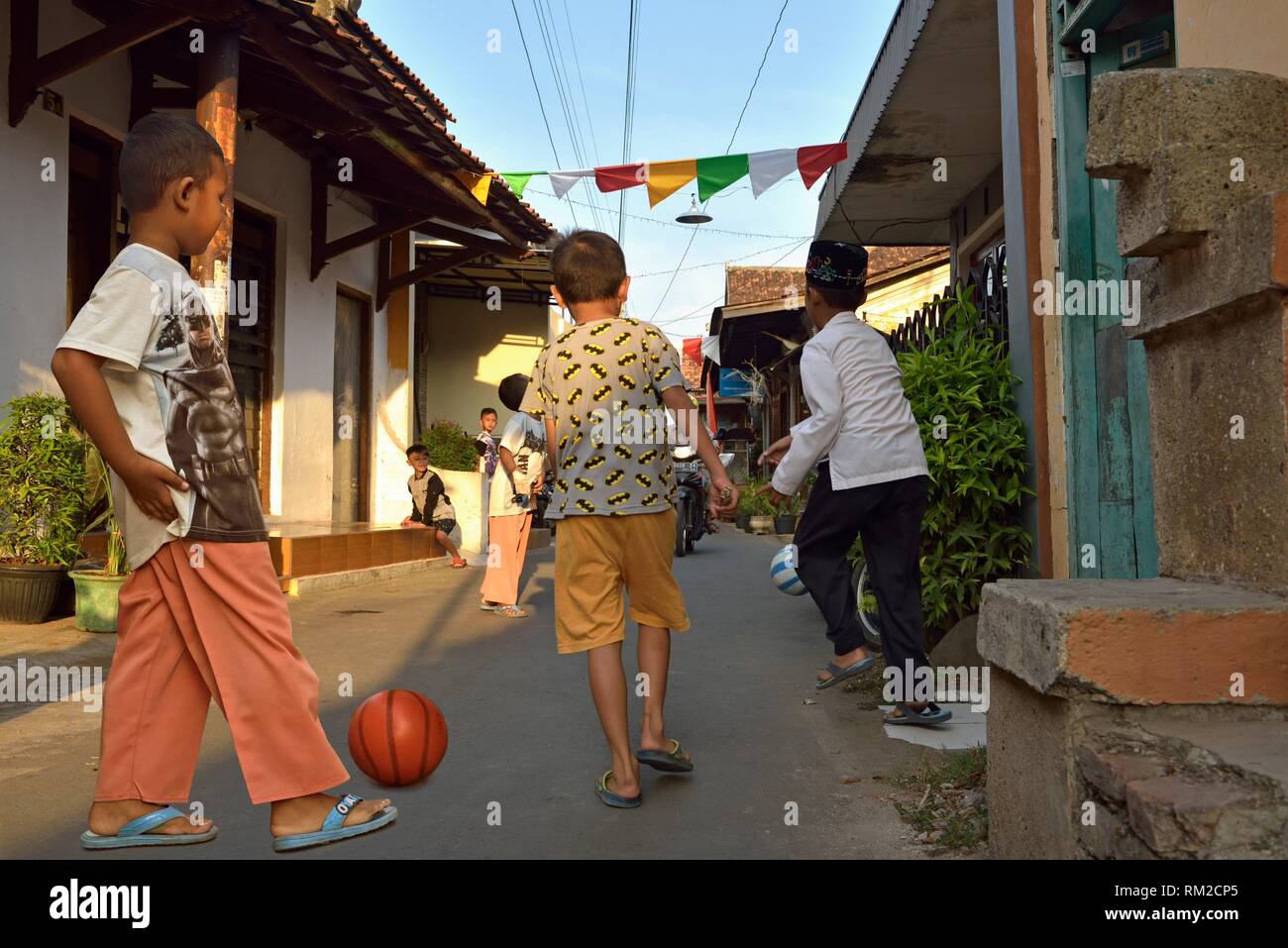 Les jeunes garçons à jouer au ballon dans une rue de village Batik Kauman (Kampung) c'est un district, avec de nombreux producteurs et artisans, Batik de Pekalongan, Java Banque D'Images
