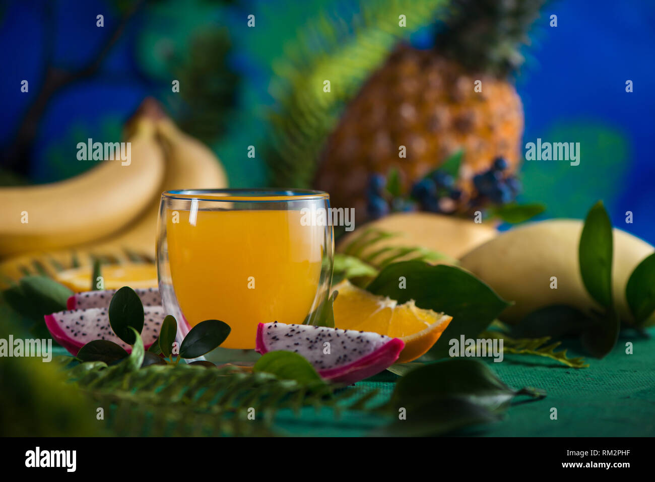 Jus frais de fruits tropicaux sur un fond bleu avec les bananes, ananas, mangue et fruit du dragon. Verre coupe avec copie espace Banque D'Images