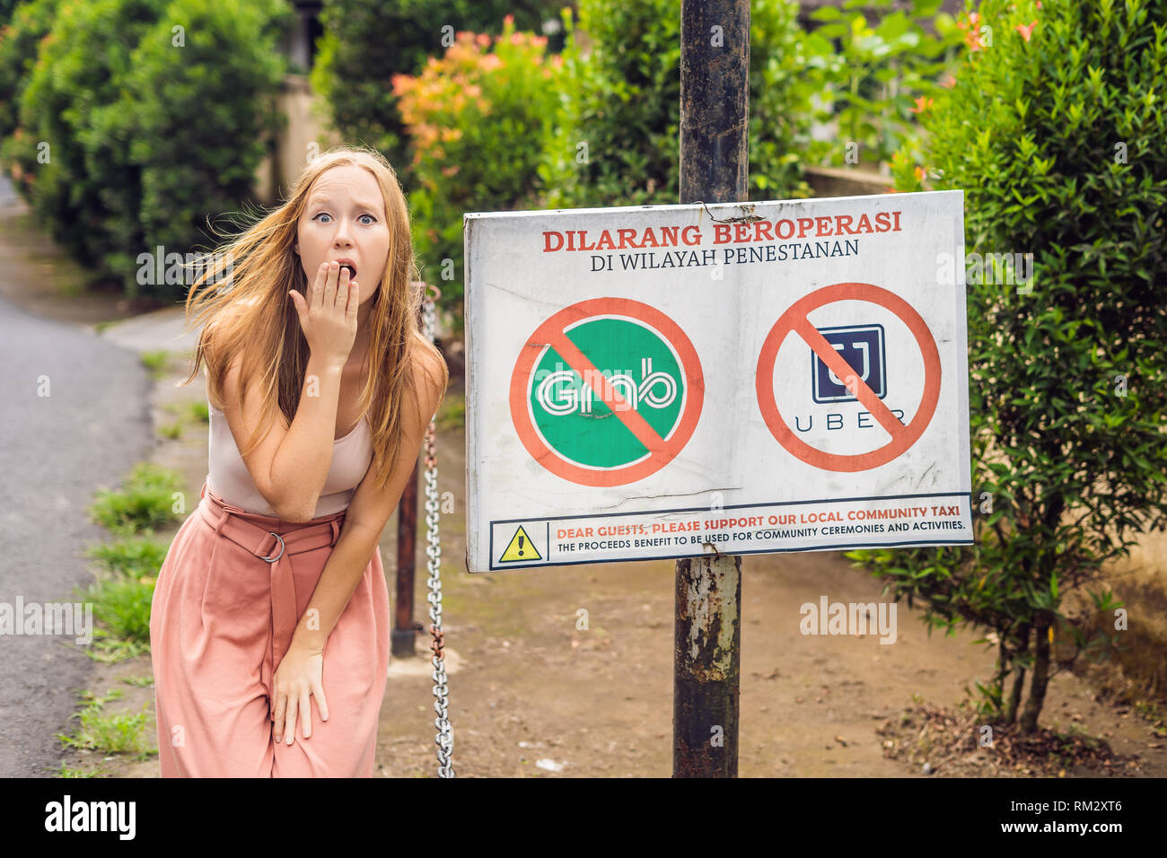 BALI, INDONÉSIE - 21 mai, 2018 : Jeune femme regarde signe de protestation sur un mur en indonésien s'opposer à l'Uber et saisir les chauffeurs de taxi se lit 'Uber et saisir Banque D'Images