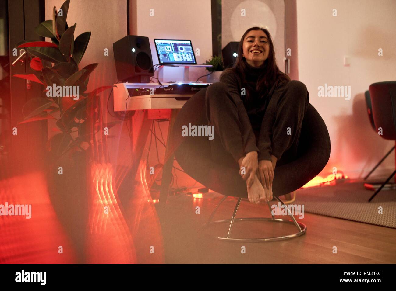 Jolie femme assis sur une chaise à côté de la musique des haut-parleurs et producteur, producteur de musique pult Banque D'Images