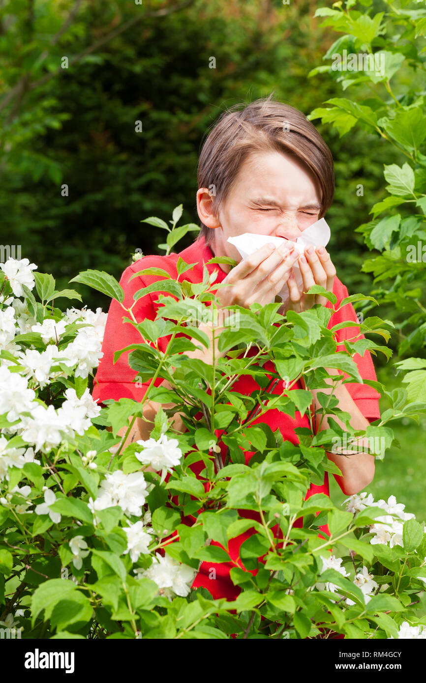 Adolescents à la grippe saisonnière l'éternuement dans un jardin de printemps - infection saisonnière concept Banque D'Images