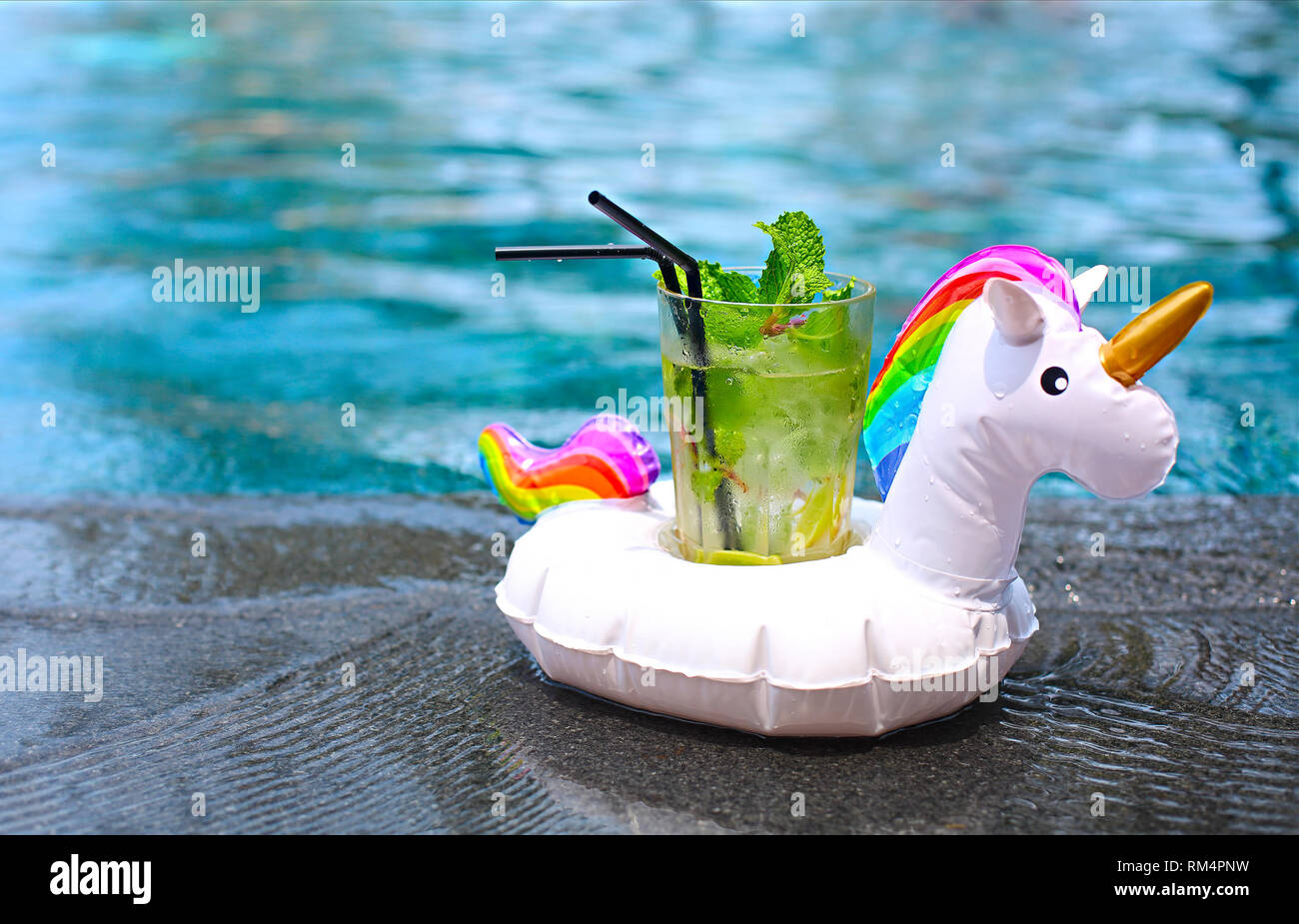 Mojito cocktail au bord d'une piscine gonflable en licorne. Concept de vacances de luxe. Piscine extérieure background Banque D'Images