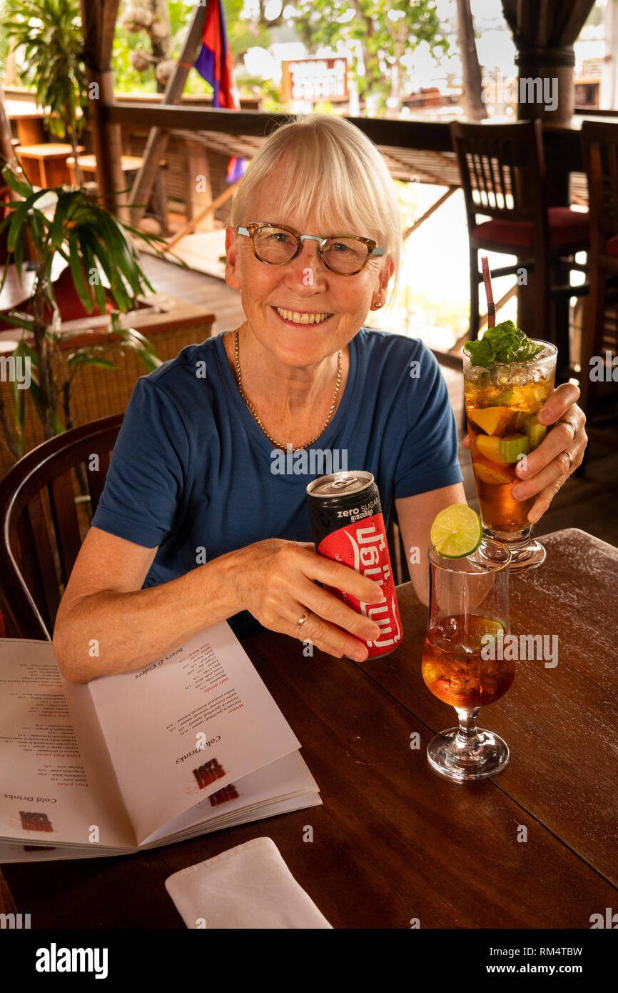 La province de Kampot, Cambodge, Kampot, 735, rue de la ville restaurant Rikitikitavi female customer avec verre de Pimms holding froid peut de Coke Zero Banque D'Images