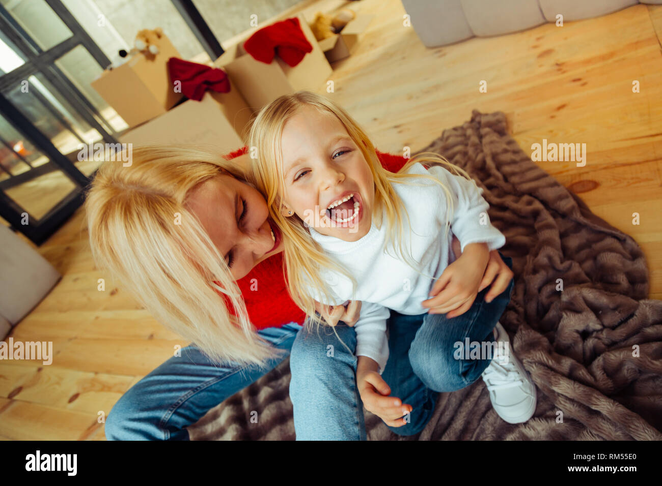Cheerful blonde girl laughing tandis que chatouillement Banque D'Images