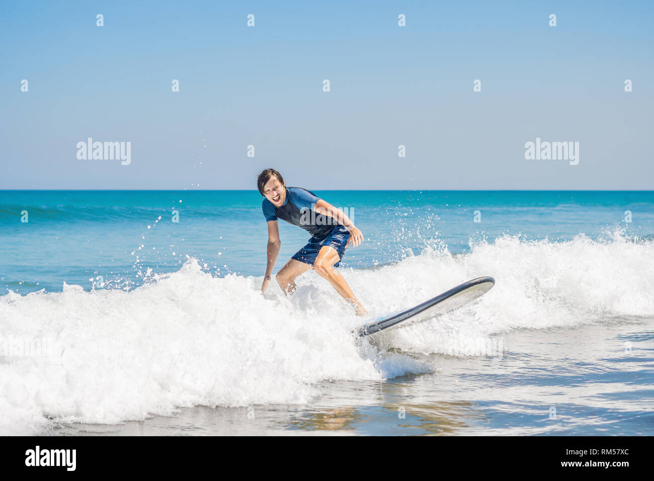 Jeune homme, Surfeur débutant apprend à surfer sur une écume de mer sur  l'île de Bali Photo Stock - Alamy