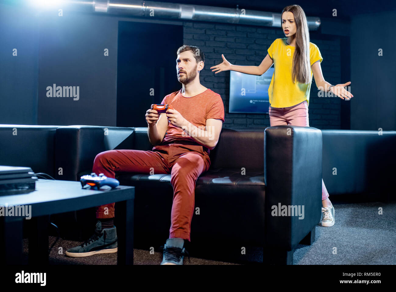 Jeune femme en colère contre son petit ami à jouer aux jeux vidéo avec console de jeux assis sur le canapé à la maison ou jouer club Banque D'Images