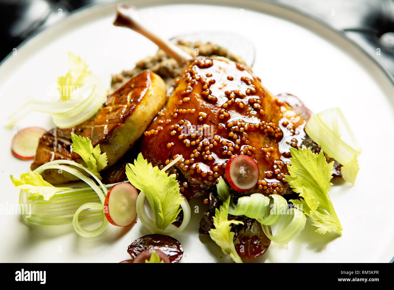 Cuisse de canard juteuse et tendre servie avec une sauce, du foie gras et du céleri Banque D'Images