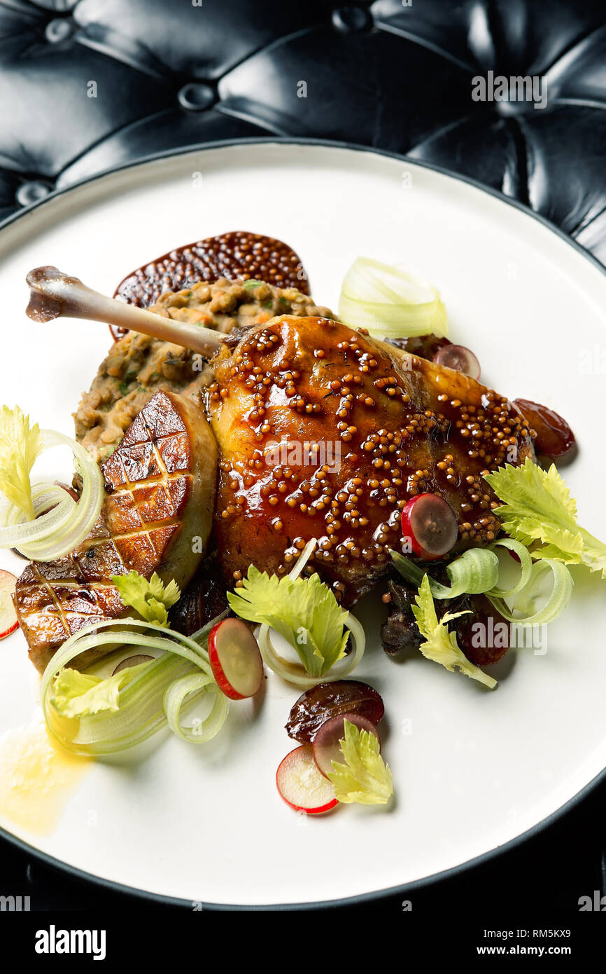 Cuisse de canard juteuse et tendre servie avec une sauce, du foie gras et du céleri Banque D'Images