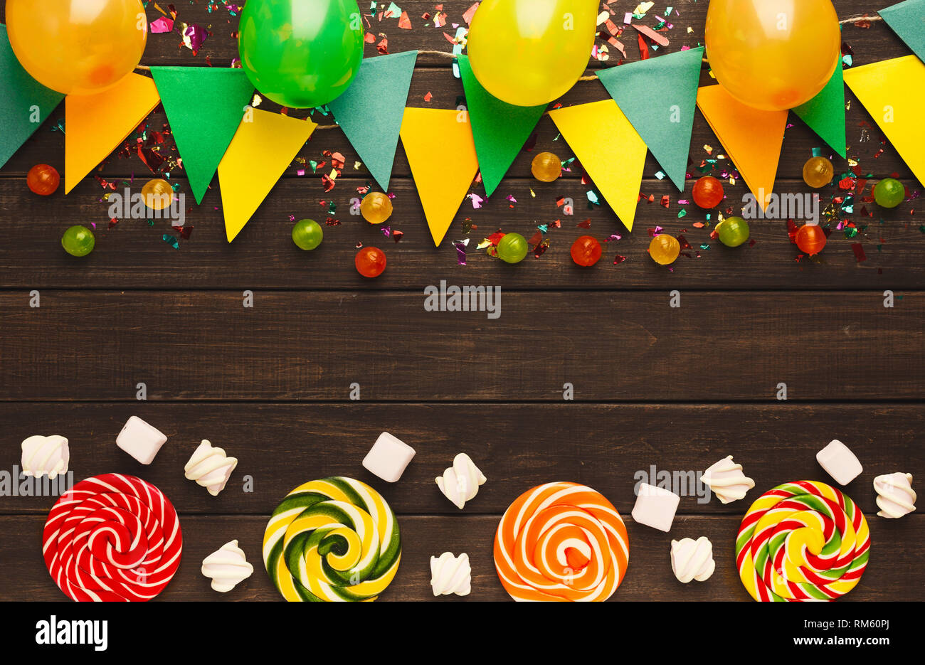 Bordure de papier coloré drapeaux Garland, confettis, ballons et spirale lolipops sur bois rustique. Décoration de fête d'anniversaire, vue du dessus, copiez spa Banque D'Images