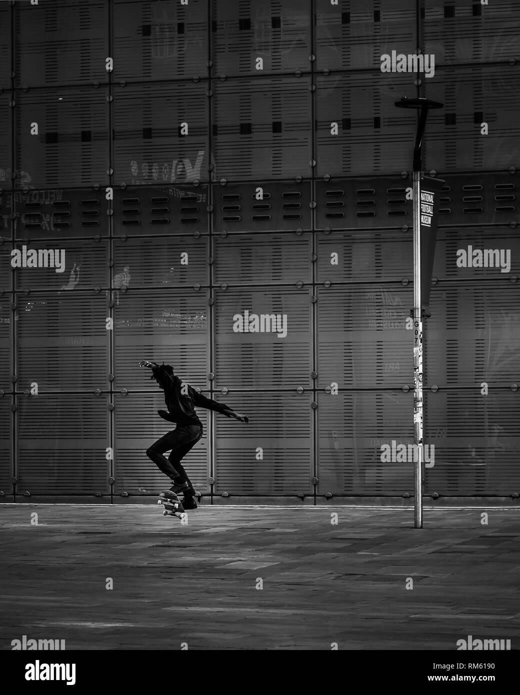 La silhouette d'un skateur professionnel effectue un tour de saut dans le centre de Manchester en noir et blanc Banque D'Images