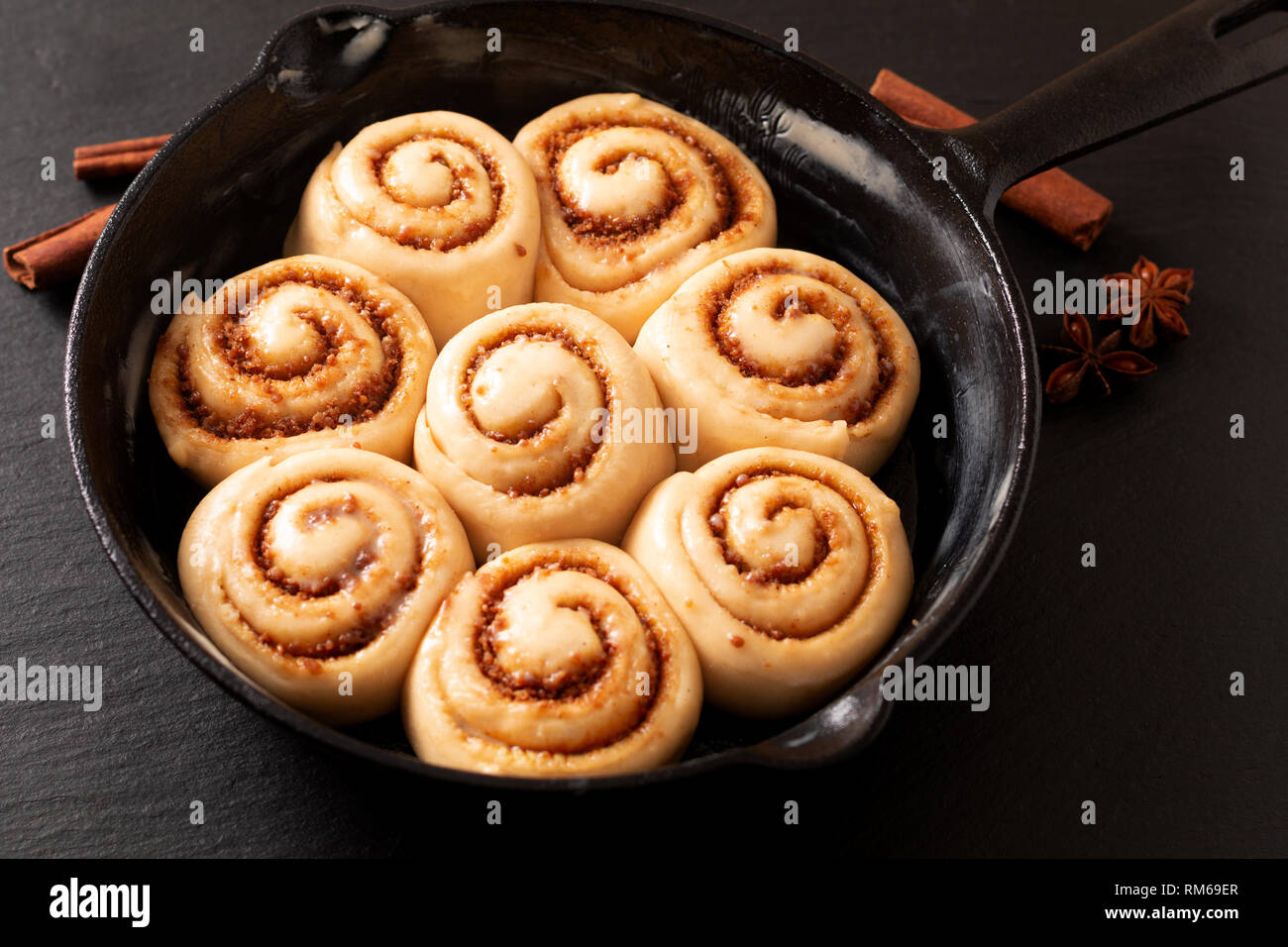 Concept de l'alimentation de la pâte gonflée à la cannelle maison soulevée avant de cuire dans une poêle poêle en fonte avec copie espace Banque D'Images