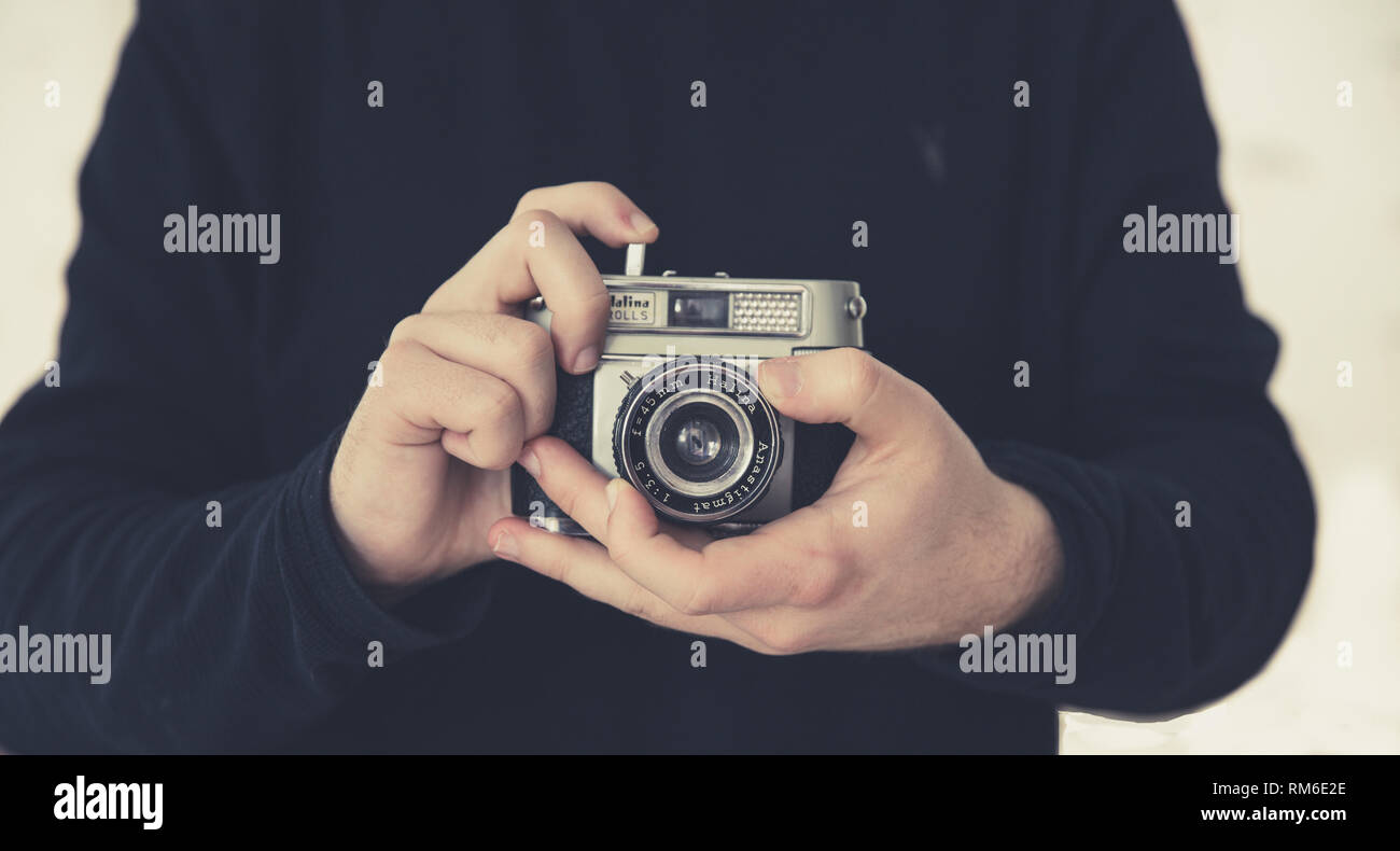 Un portrait d'un homme photographe portant l'objectif tout en maintenant un style rétro ou old fashioned caméra 35mm dans un style passe-temps libre Banque D'Images