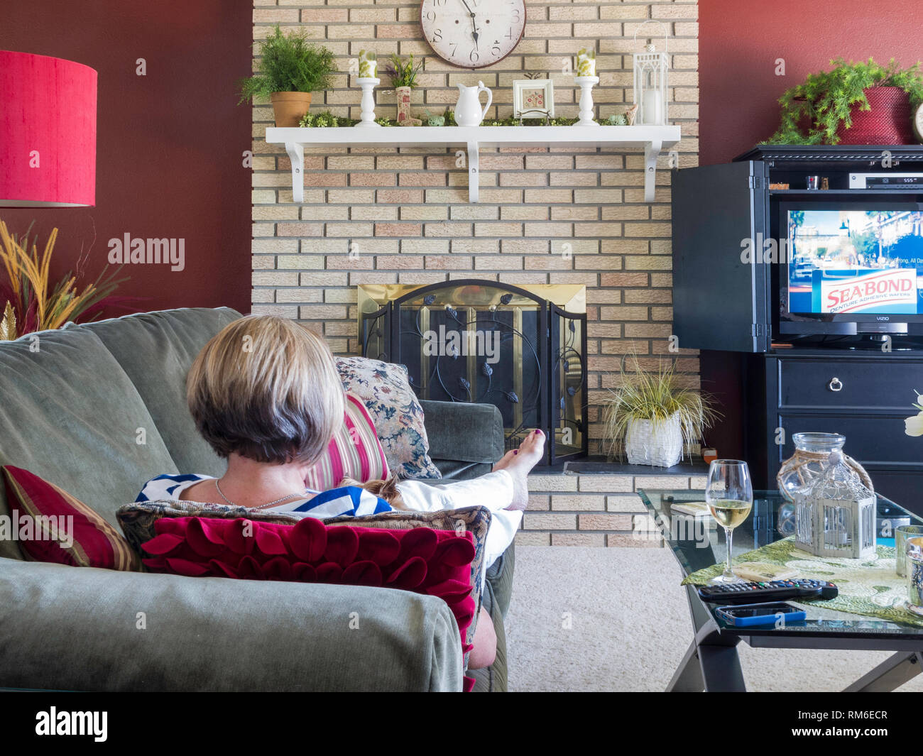 Mature Woman relaxing regarder la télévision et prendre un verre de vin, USA Banque D'Images