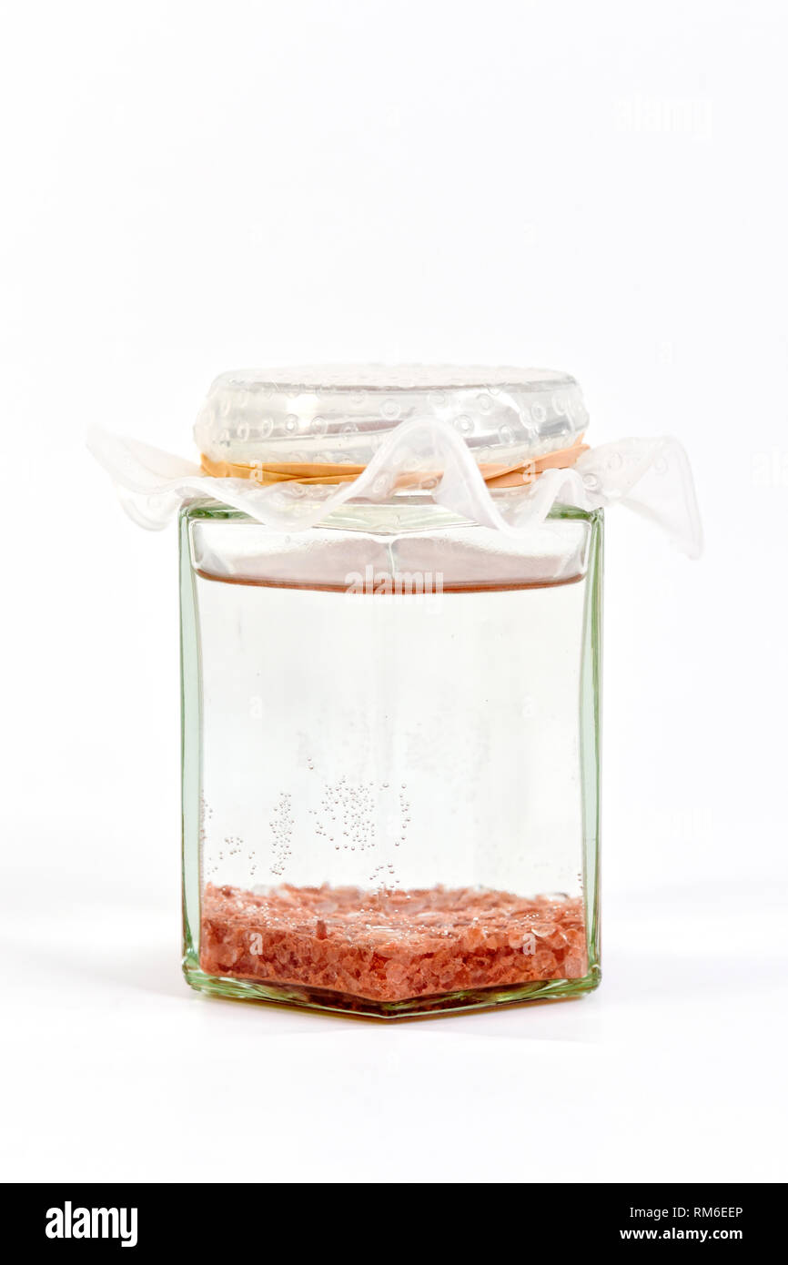 Seul le sel de l'Himalaya, appelé aussi seule l'eau, dans un bocal en verre sur un fond blanc. Banque D'Images