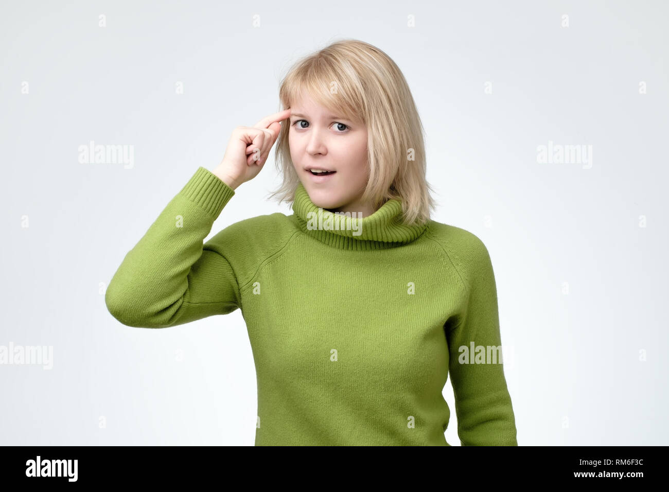 Woman gesturing, tordant son index au temple, lui demandant de bien réfléchir Banque D'Images