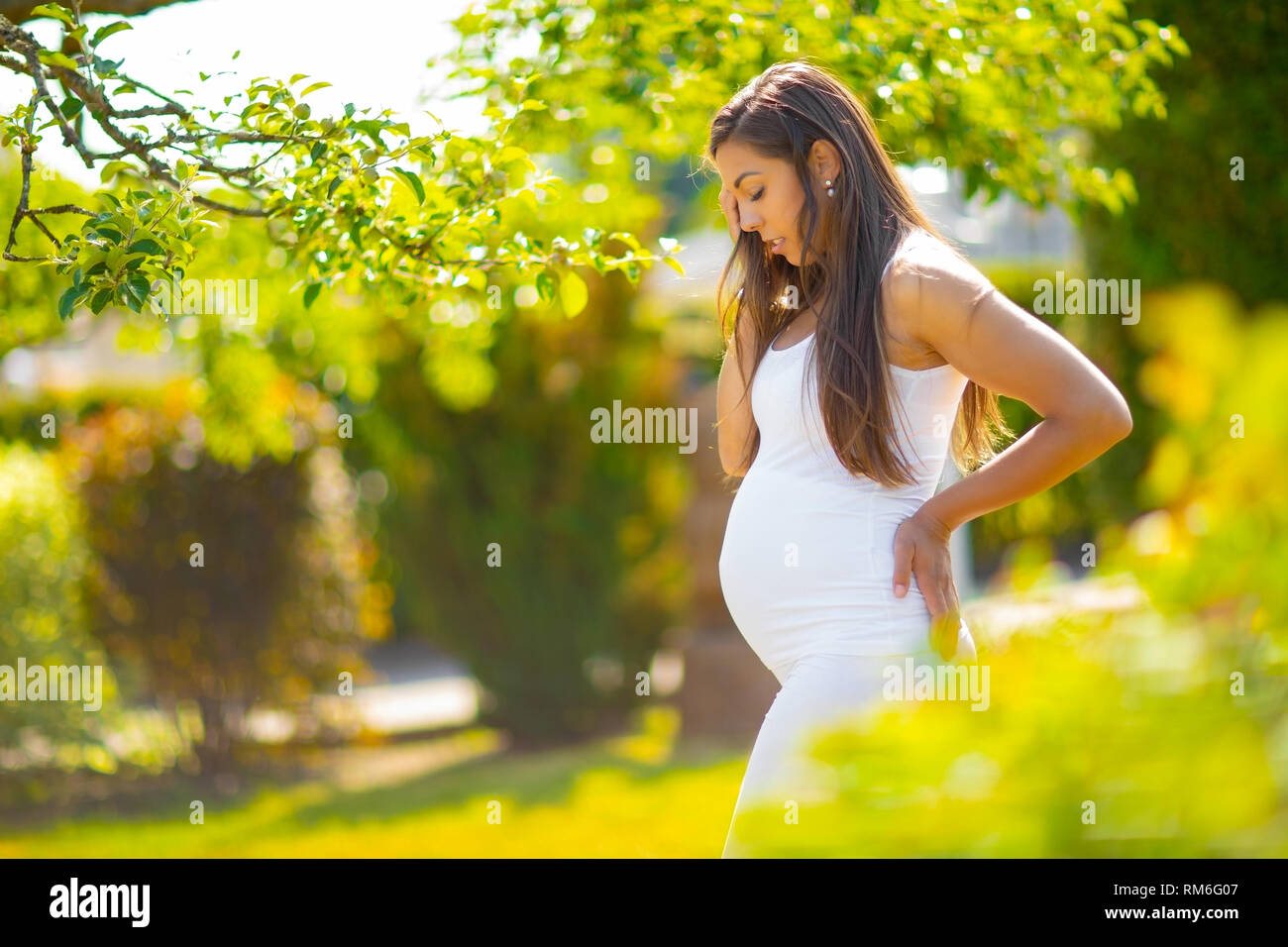 Femme enceinte dans beau jardin en regardant son ventre Banque D'Images