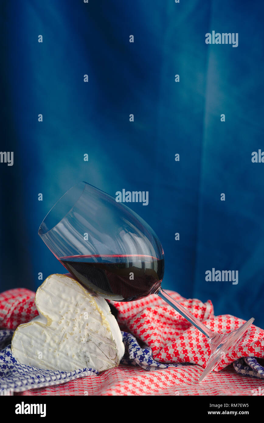 La composition avec Neufchatel, fromage normand (A.O.P.) et d'un verre de vin, sur un fond bleu. Banque D'Images