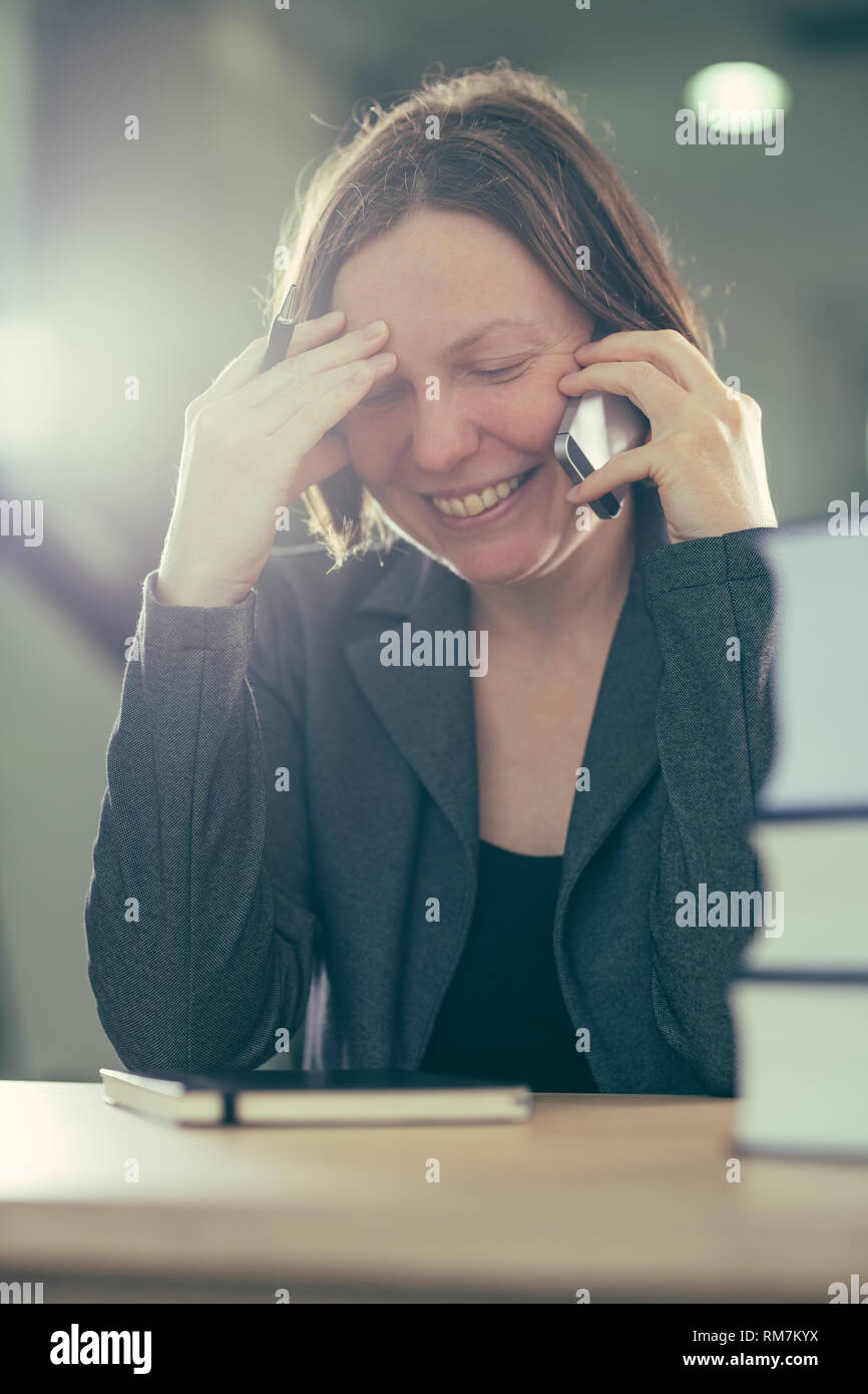 Happy smiling businesswoman talking on mobile phone depuis son bureau 24, selective focus Banque D'Images