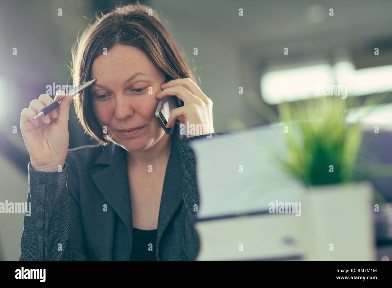 Happy smiling businesswoman talking on mobile phone depuis son bureau 24, selective focus Banque D'Images