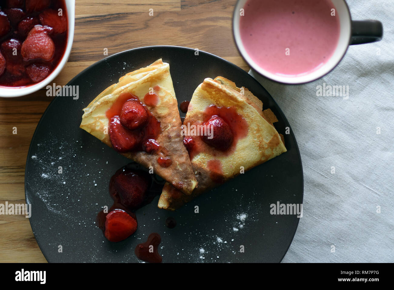 Crêpes maison avec du fromage cottage et les fraises dans une assiette. Fond de bois. Banque D'Images