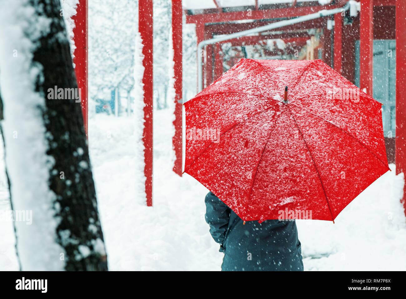 Triste et seule femme parapluie rouge sous la neige en hiver grâce à l'environnement urbain Banque D'Images
