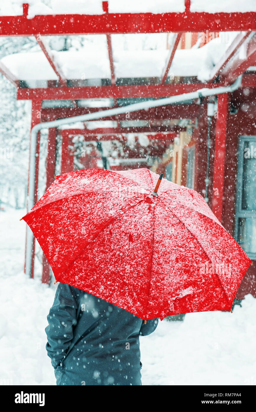Triste et seule femme parapluie rouge sous la neige en hiver grâce à l'environnement urbain Banque D'Images
