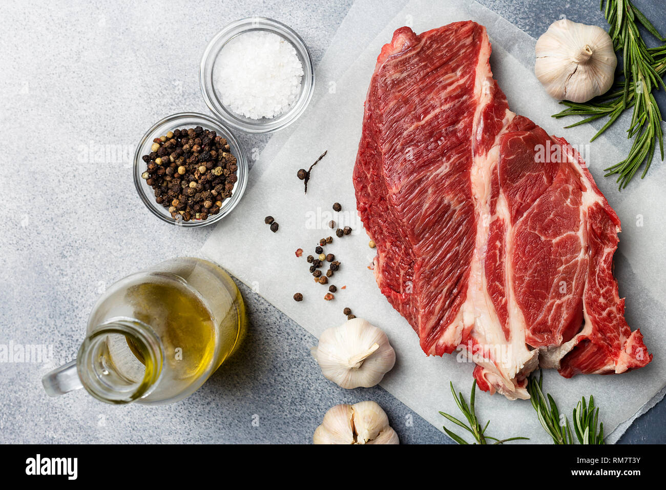 Morceau de viande fraîche de boeuf aux herbes, l'huile et l'ail sur fond gris. Concept d'aliments sains, vue de dessus. Table top Banque D'Images Morceau de viande fraîche de boeuf aux herbes, l'huile et l'ail sur fond gris. Concept d'aliments sains, vue de dessus. Table top Banque D'Images
