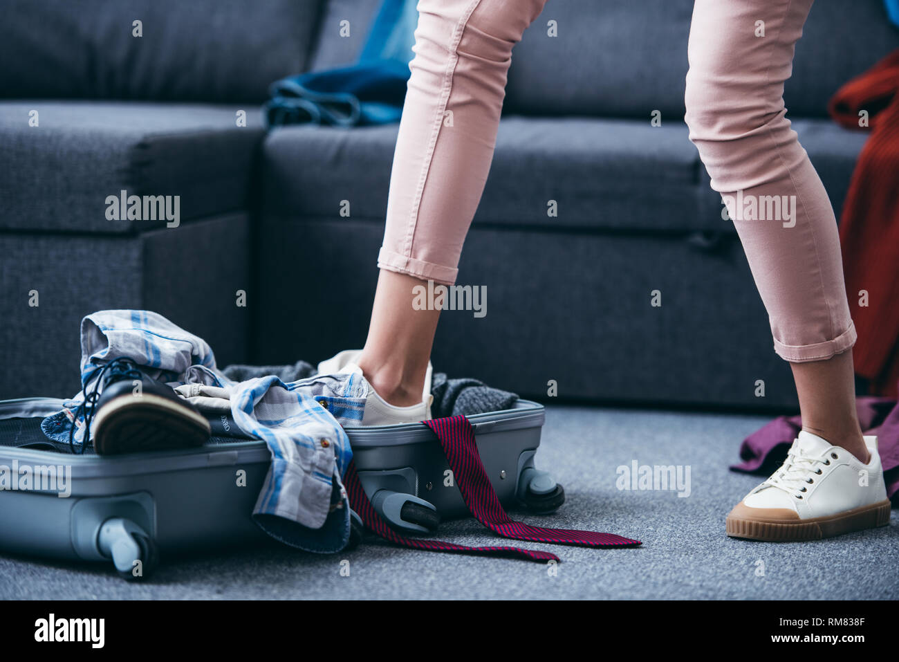 Portrait de femme en poussant les vêtements dans une valise à jambe après sa rupture avec petit ami Banque D'Images