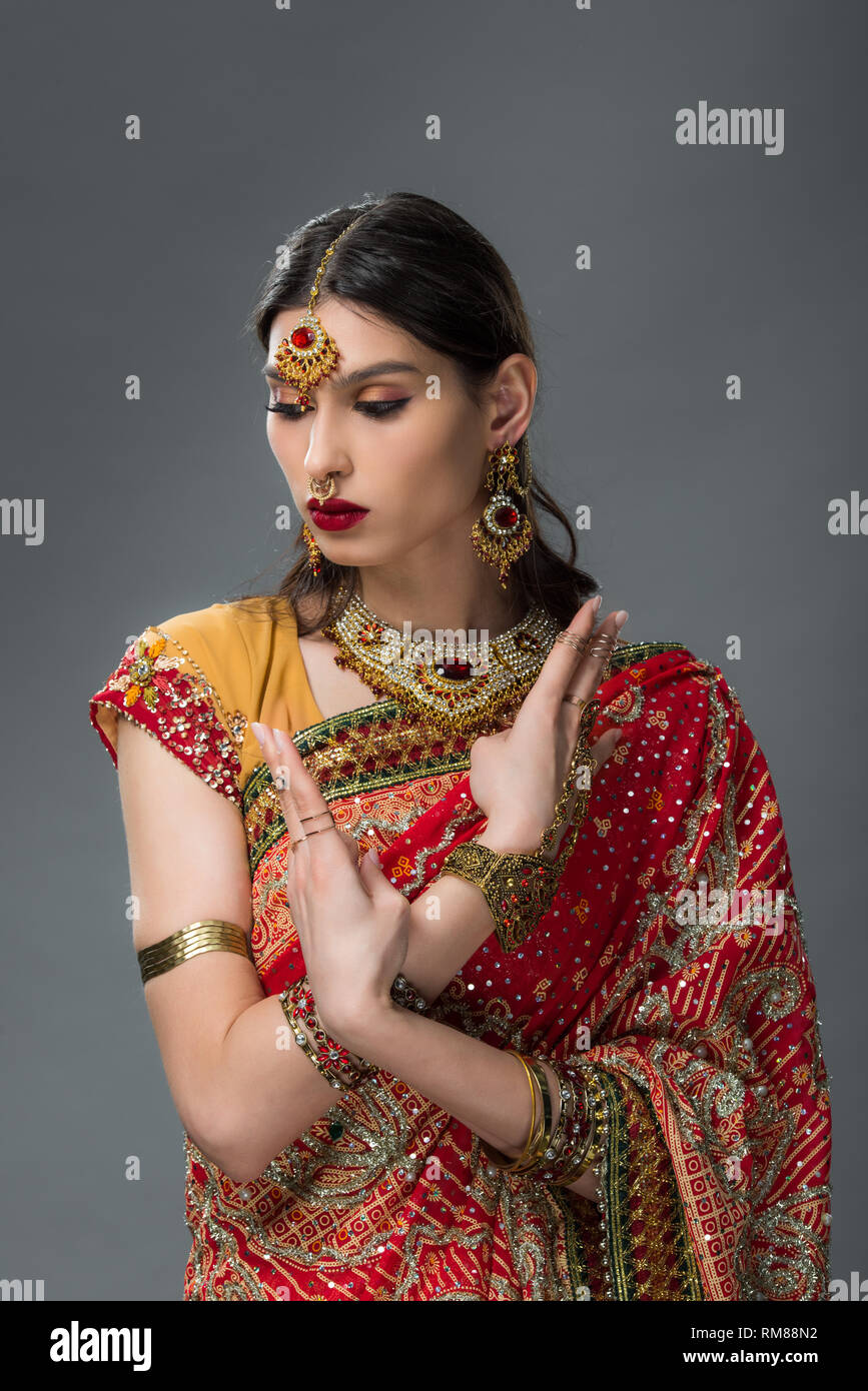 Belle femme indienne posant dans des vêtements traditionnels montrant mudra, isolé sur gris Banque D'Images