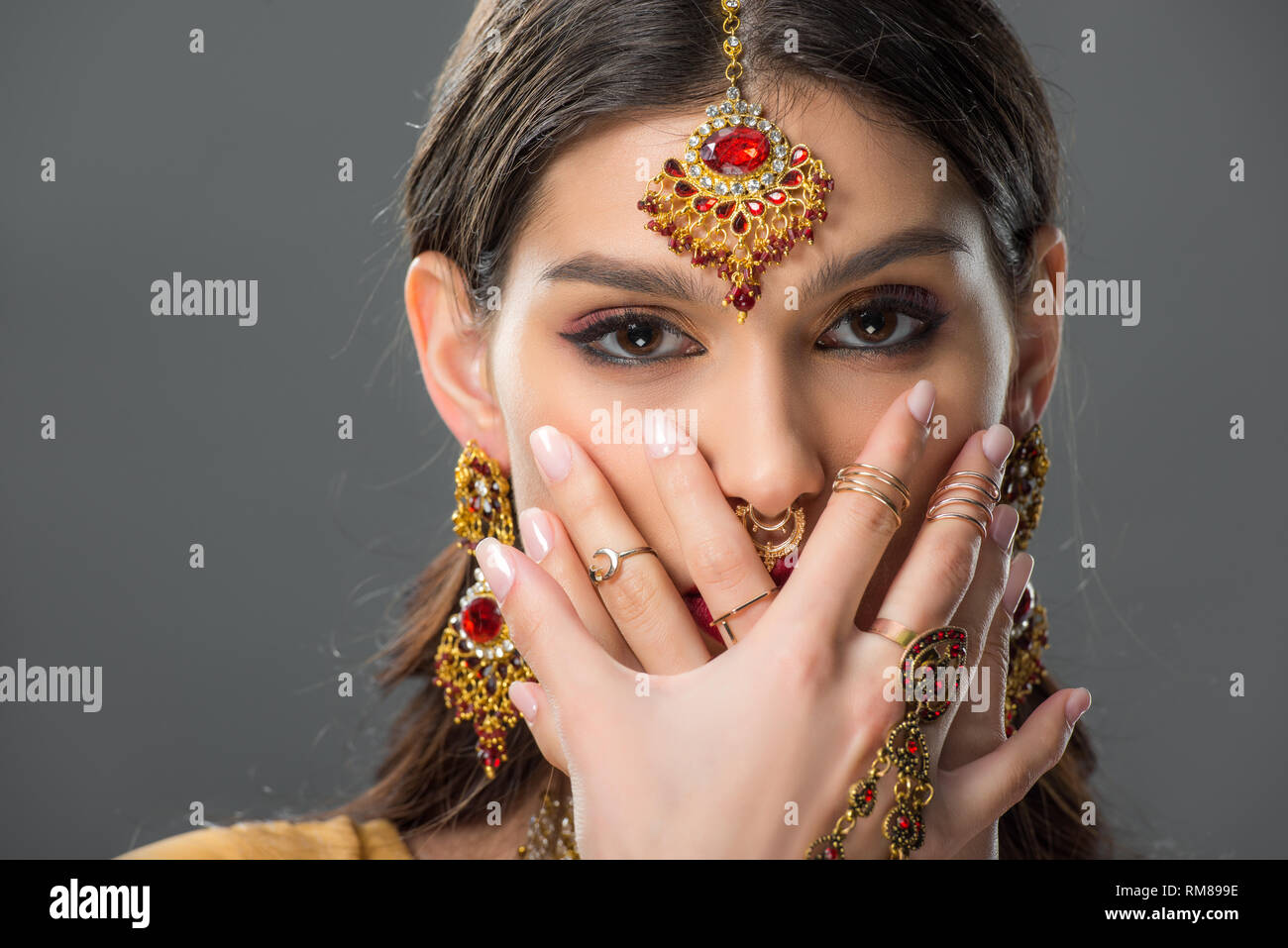 Belle femme indienne avec bindi fermer visage avec les mains, isolé sur gray Banque D'Images