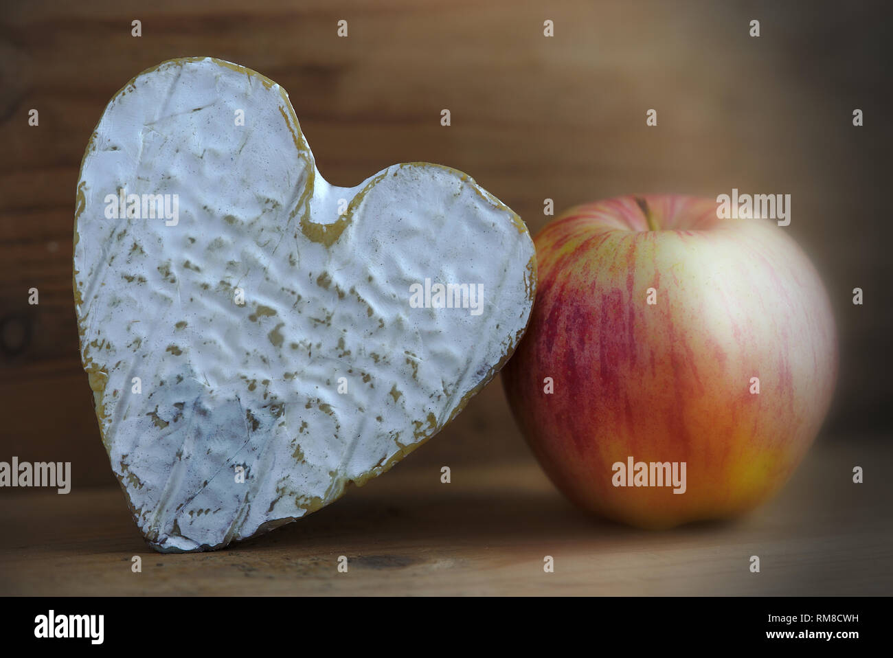 Nature morte avec un fromage normand Neufchatel (A.O.P.) et une pomme, sur fond de bois Banque D'Images