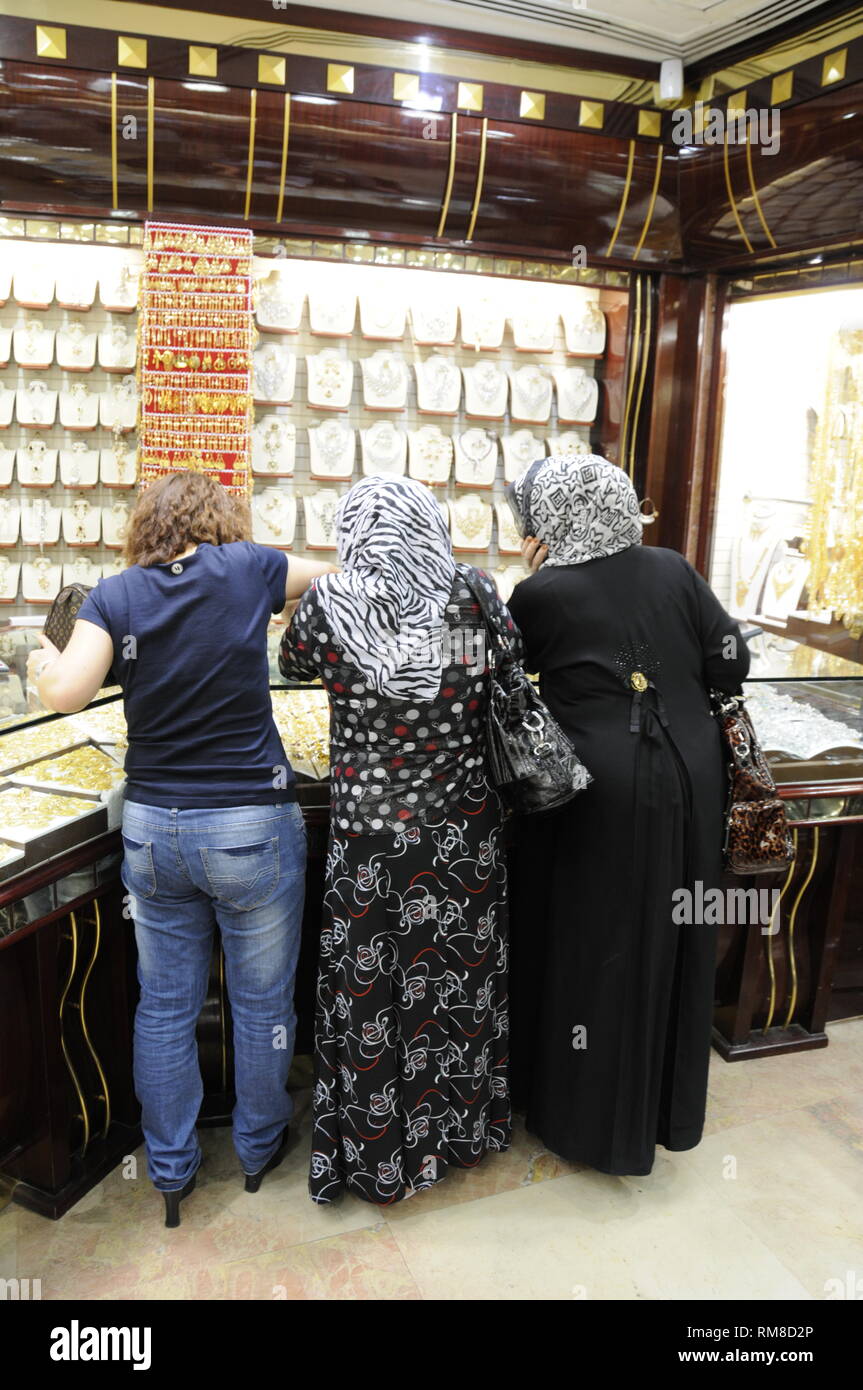 Les clients ayant un Emirati parcourir. Derrière le comptoir sont deux bijoutiers détaillants Emirati à l'intérieur d'un dans le marché de l'or dans le quartier de Deira à Dubaï Banque D'Images