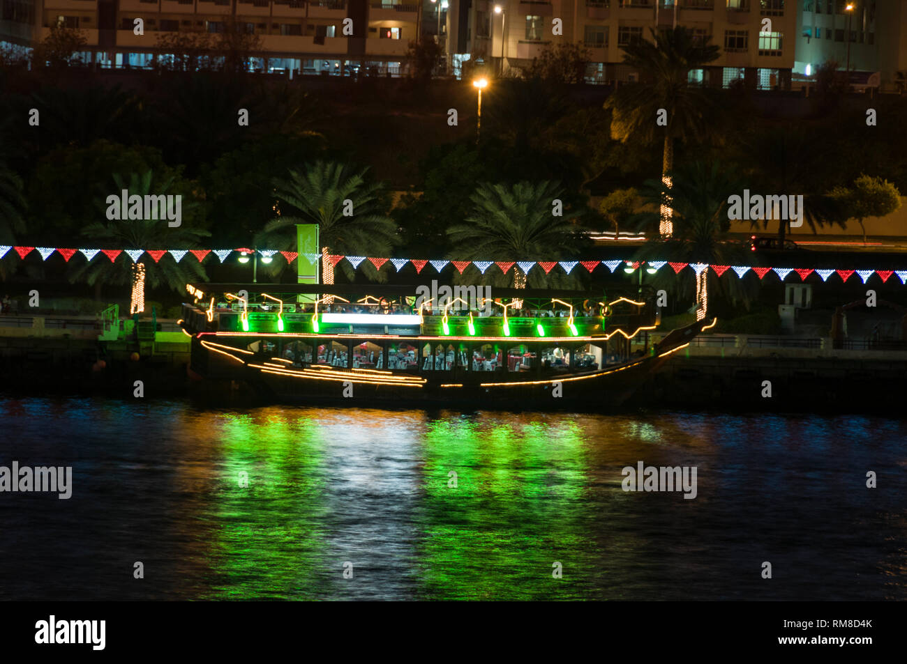 Un boutre arabe illuminé (bateau) converti en un restaurant flottant amarré le long de la Crique de Dubaï à Dubaï aux Emirats Arabes Unis, (EAU). Banque D'Images