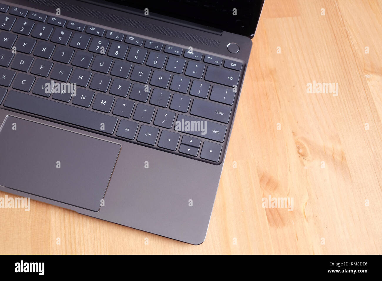 Partie d'ouvrir un ordinateur portable avec clavier, touchpad et vide de protection d'écran pour ordinateur portable noir ouvert sur la surface de la table en bois beige gros plan Vue de dessus Banque D'Images