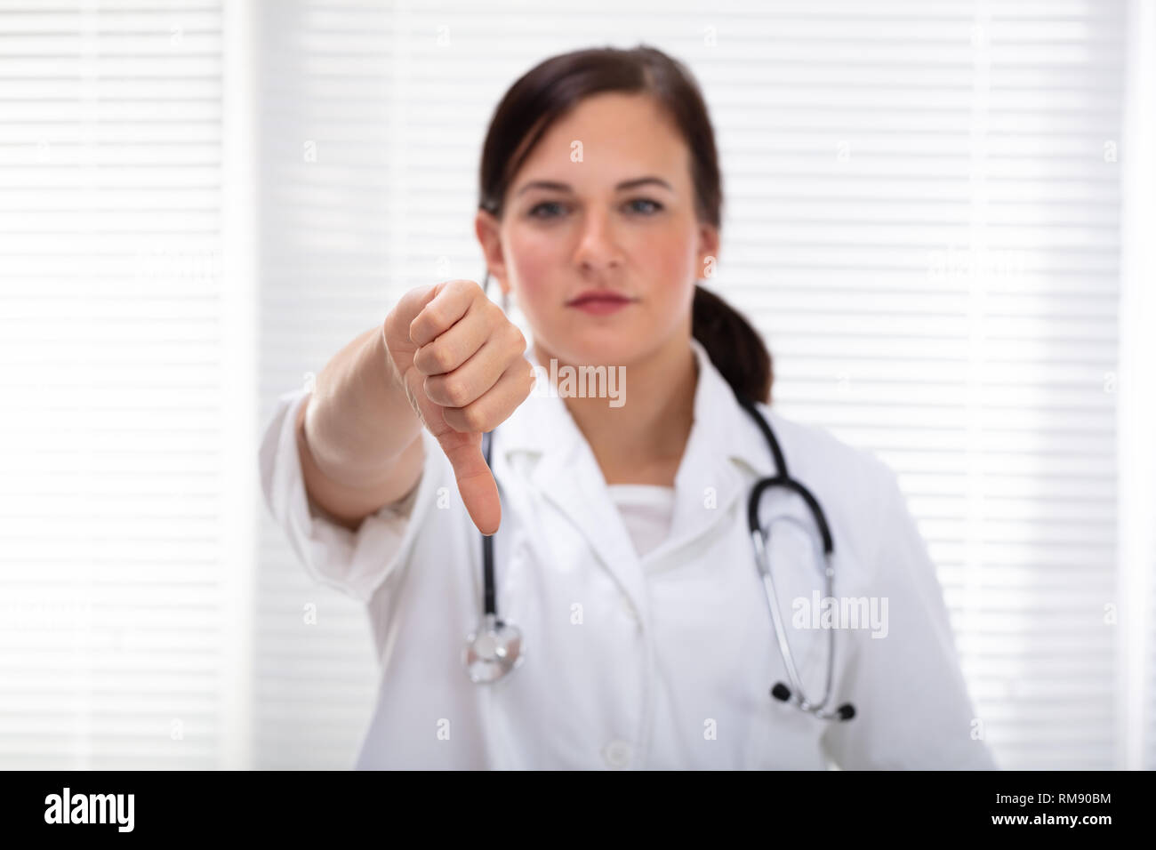 Sad Female Doctor Showing Thumb Down Sign In Clinic Banque D'Images