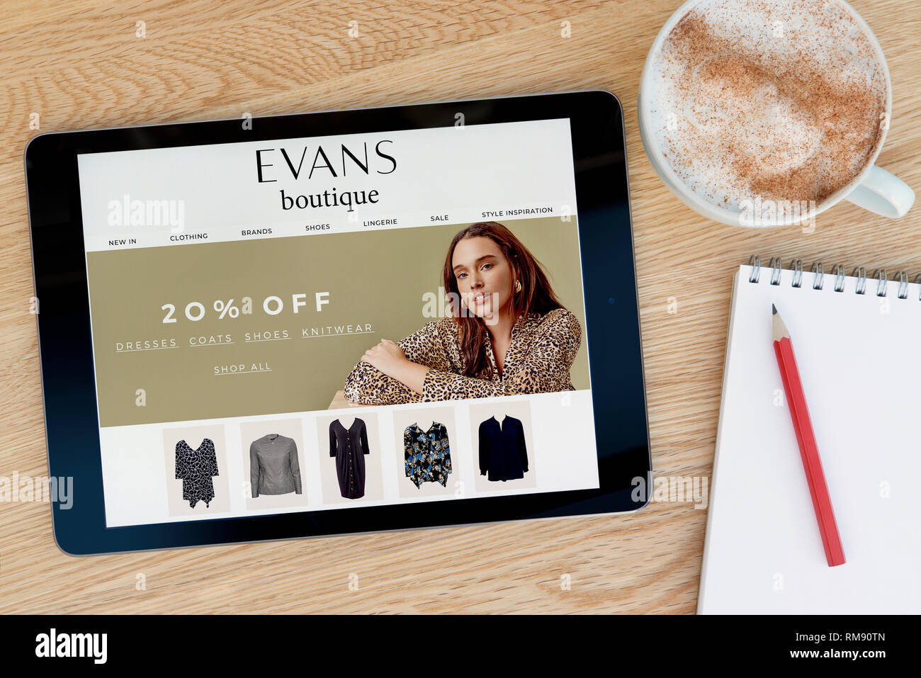 La Boutique site dispose d'Evans sur un iPad tablet device qui repose sur une table en bois à côté d'un bloc-notes (usage éditorial uniquement). Banque D'Images