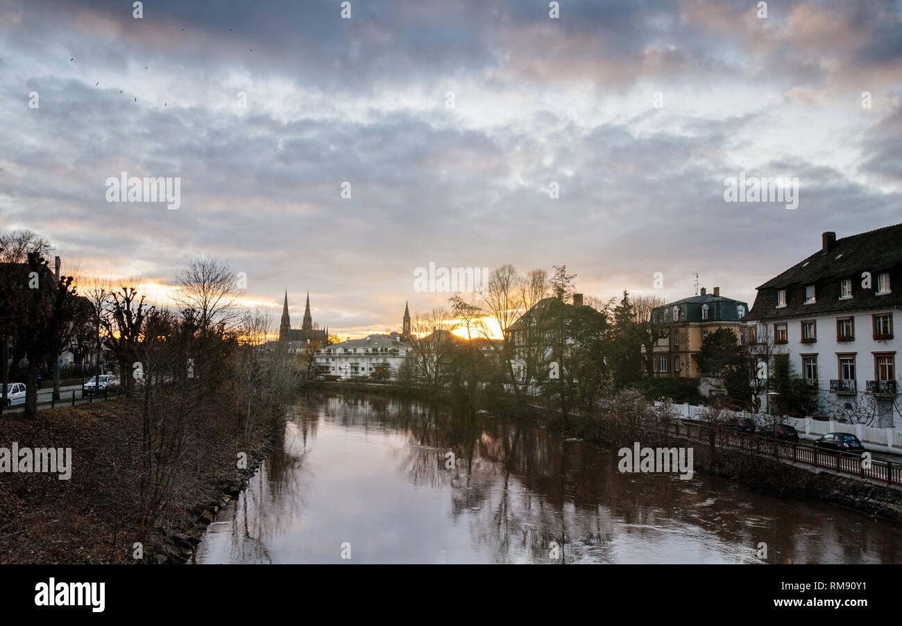 Coucher du soleil avec Strasbourg et nuageux ciel ensoleillé avec Reformed Church Saint Paul et de l'Ill, voitures garées et maisons Banque D'Images