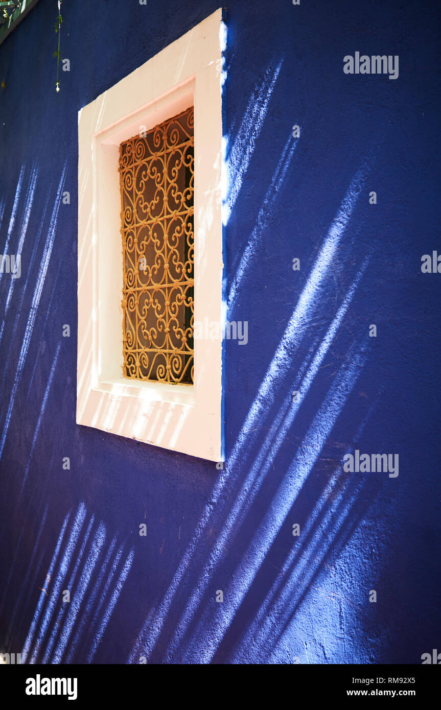 Fenêtre en fer forgé doré détails de conception dans un mur bleu au jardin botanique du Jardin Majorelle, Marrakech, Maroc. Banque D'Images