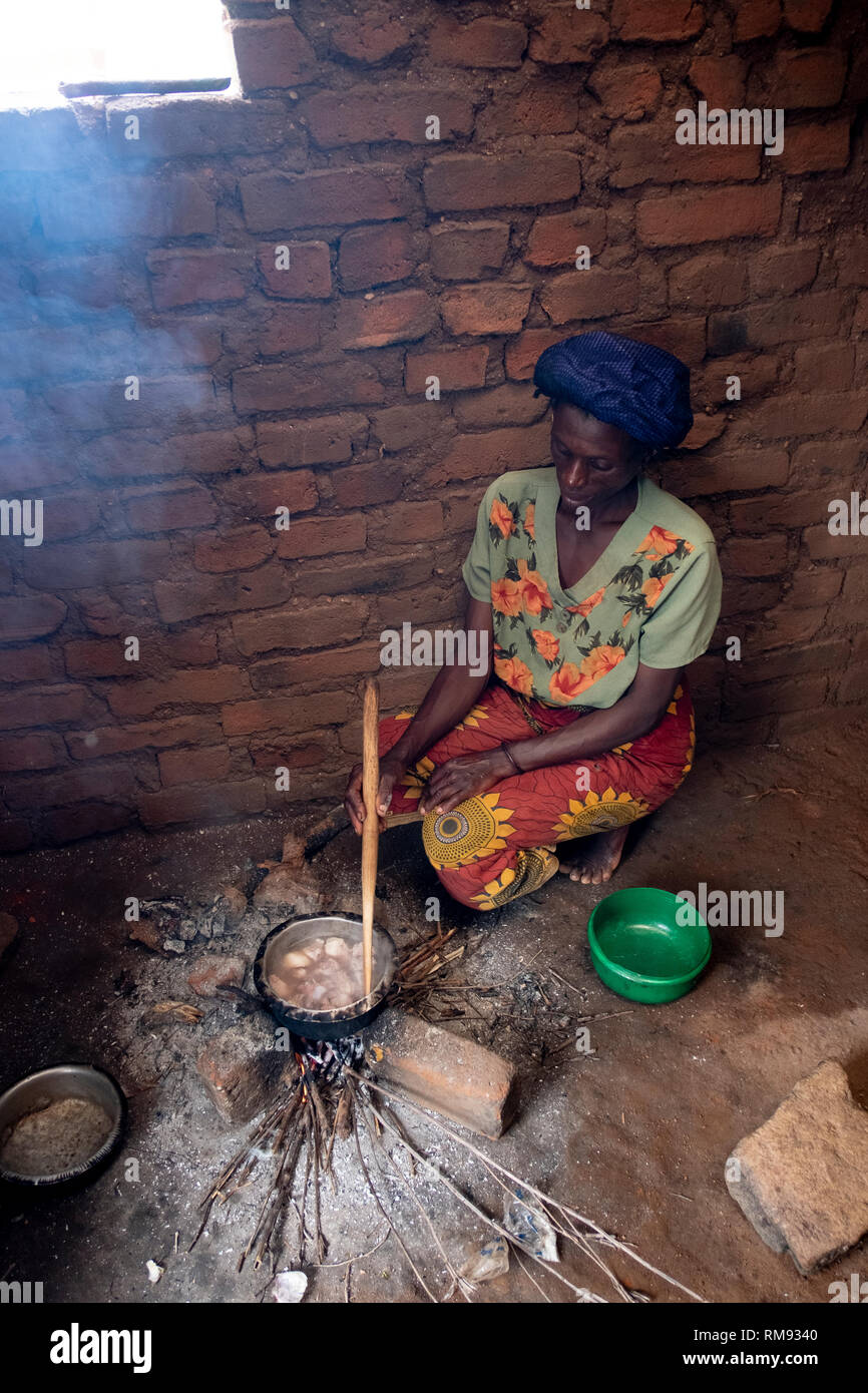 Une femme prépare un repas dans une cabane dans Jubele, Dowa, Malawi Banque D'Images