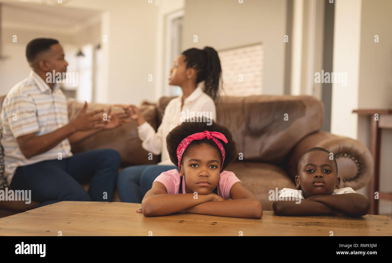 Les enfants afro-américains s'appuyant sur table tout en soutenant les parents sur le canapé Banque D'Images