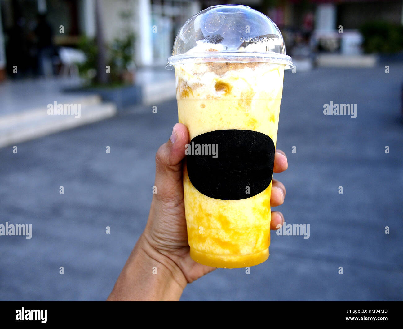 Photo d'une main tenant une grande tasse de mango slushie Banque D'Images
