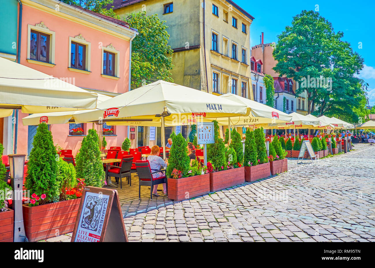 Cracovie, Pologne - 21 juin 2018 : La ligne de l'été avec une terrasse immense de umbrelas restaurants touristiques populaires dans la rue Szeroka dans Kazimier historique Banque D'Images