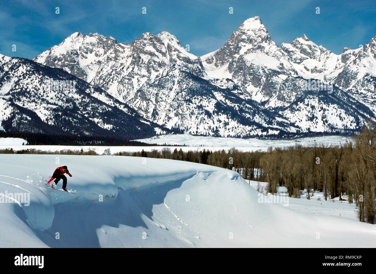 Une audacieuse jeune snowboarder sails off une étagère de neige immaculée en vue de l'impressionnante chaîne de montagnes Teton à Grand Teton National Park près de Jackson Hole, Wyoming, USA. Banque D'Images Une audacieuse jeune snowboarder sails off une étagère de neige immaculée en vue de l'impressionnante chaîne de montagnes Teton à Grand Teton National Park près de Jackson Hole, Wyoming, USA. Banque D'Images