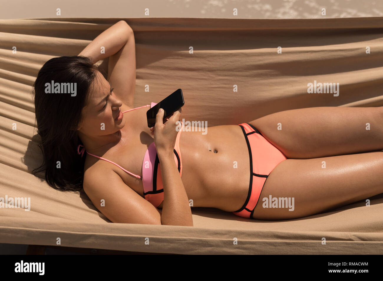 Young Woman talking on mobile phone tout en vous relaxant sur hamac Banque D'Images