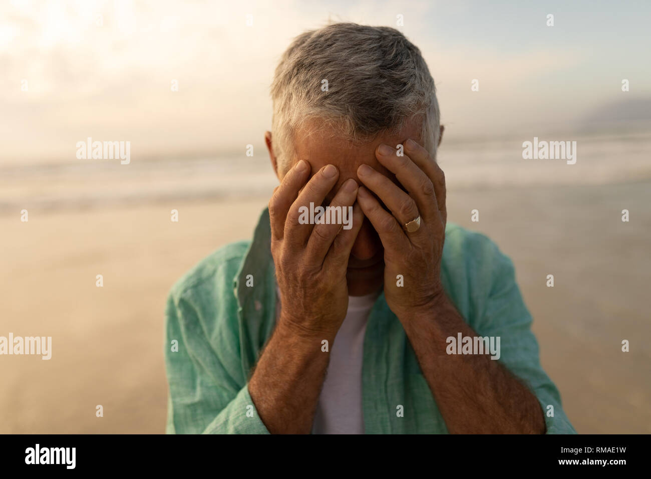 Man couvrant son visage en étant debout sur la plage Banque D'Images