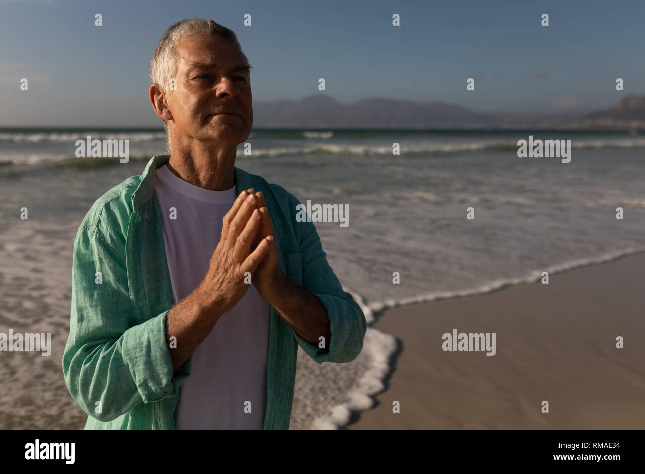Man prier avec les yeux fermés sur la plage Banque D'Images