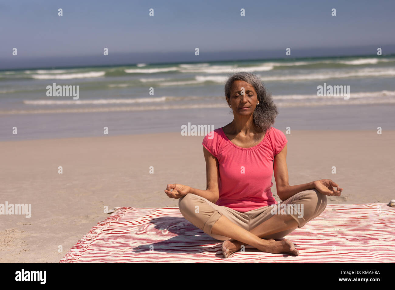 Senior woman with eyes closed faisant du yoga la plage Banque D'Images