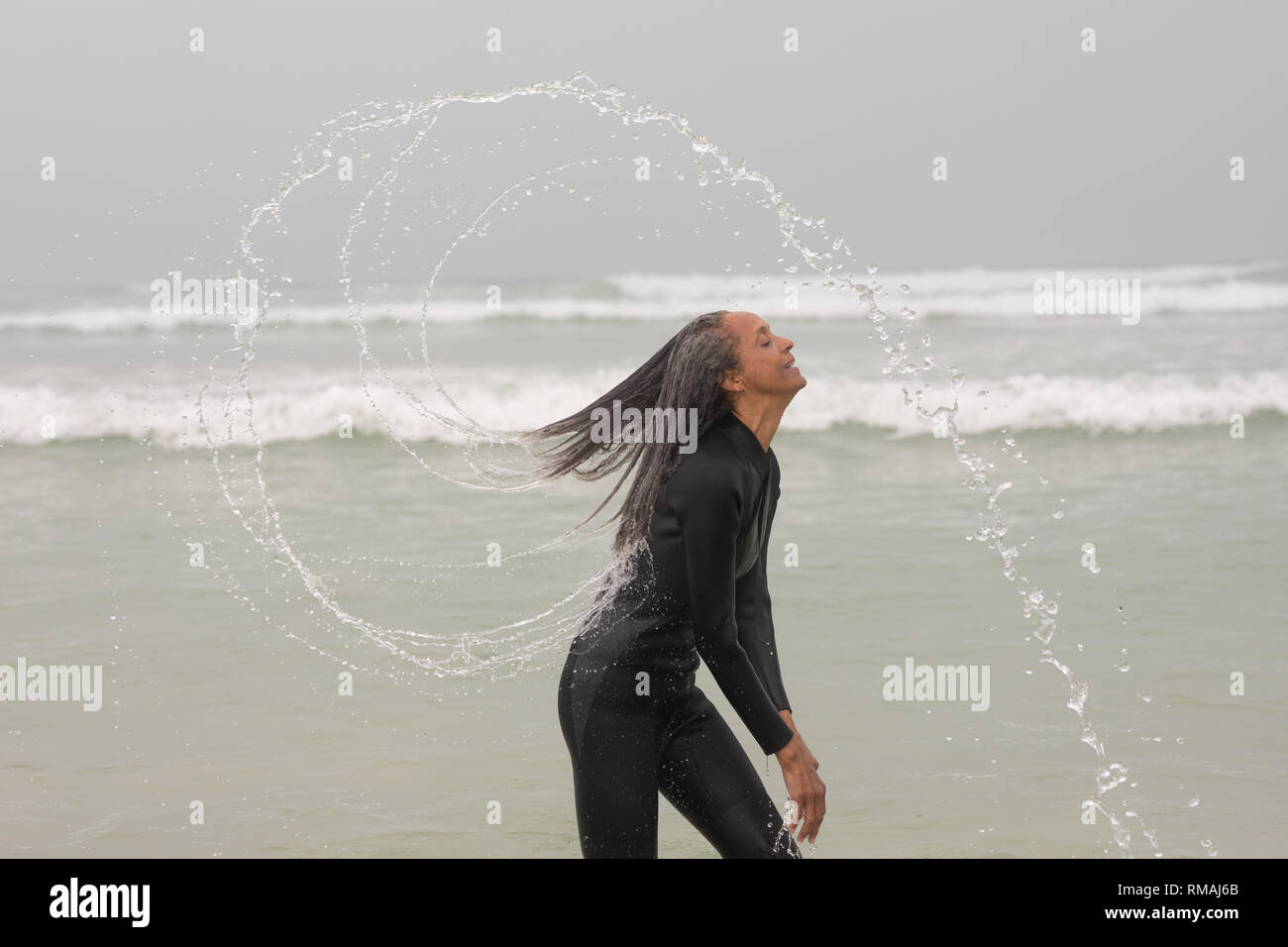 Happy female surfer les projections d'eau avec ses cheveux à la plage de Banque D'Images