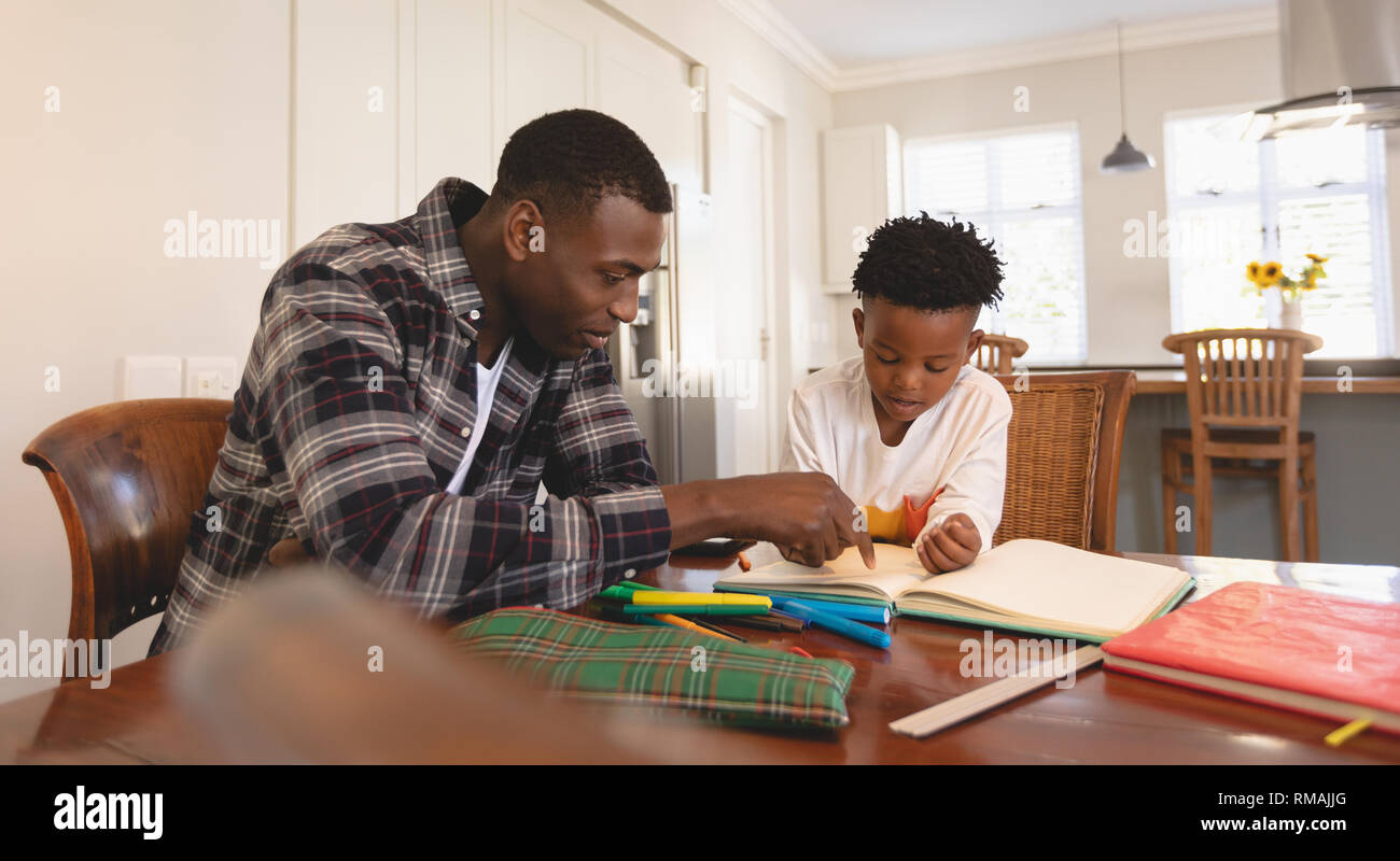 African American father aider son fils à faire ses devoirs à la table Banque D'Images