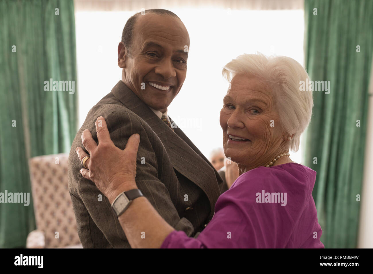 Vue latérale d'happy senior couple looking at camera while dancing Banque D'Images